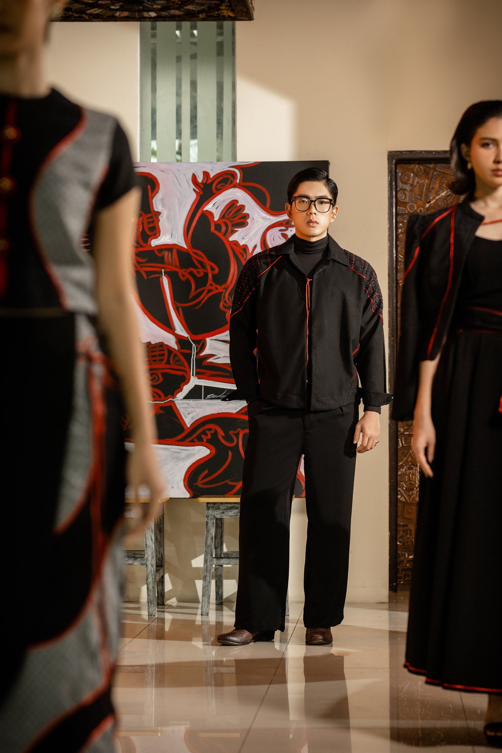 Models in black and red from Crimson Drive, standing before the red-line painting